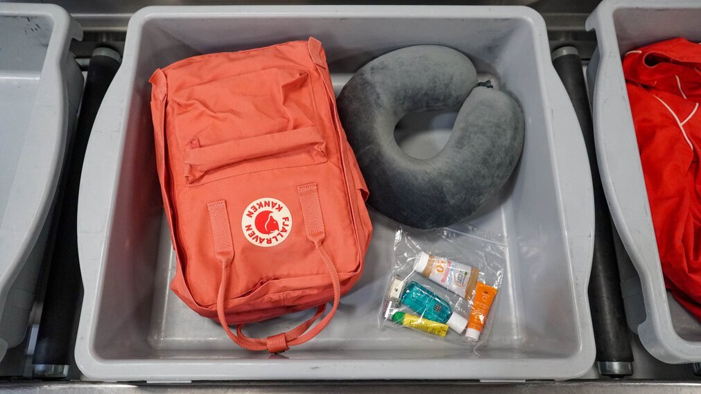 Rucksack, liquids bag and travel pillow in security tray